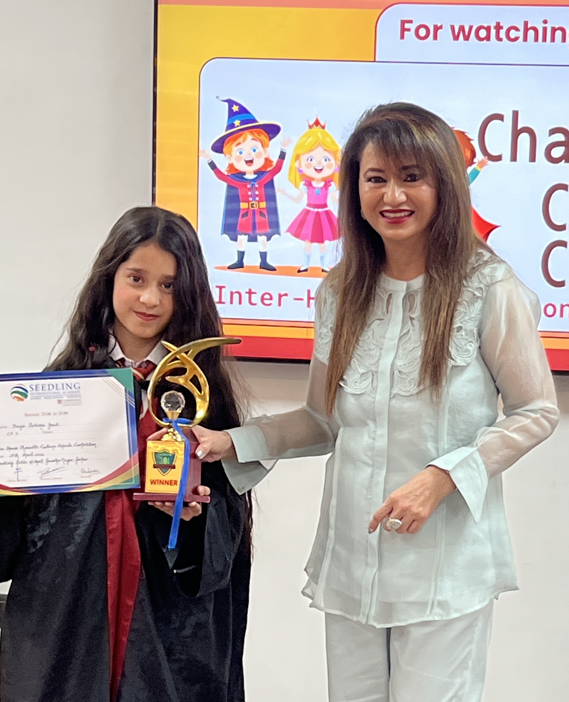 Student proudly holding a golden trophy and achievement certificate